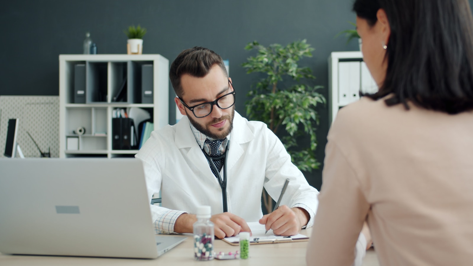 Profissional registrando informações enquanto conversa com paciente em consultório